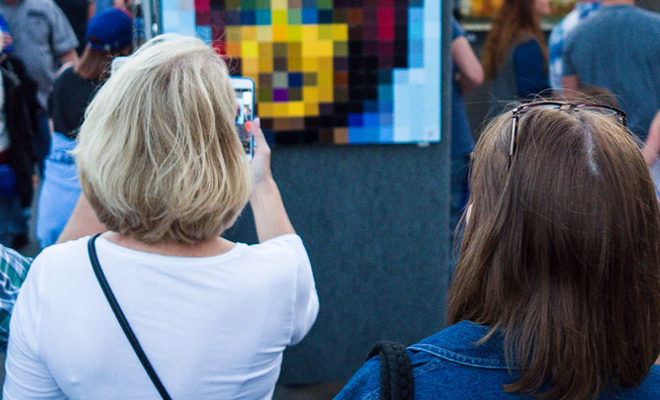 a woman taking a photo of a piece of art at an outdoor festival